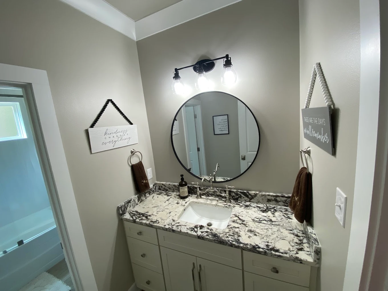 Bathroom vanity with a patterned stone countertop and round mirror