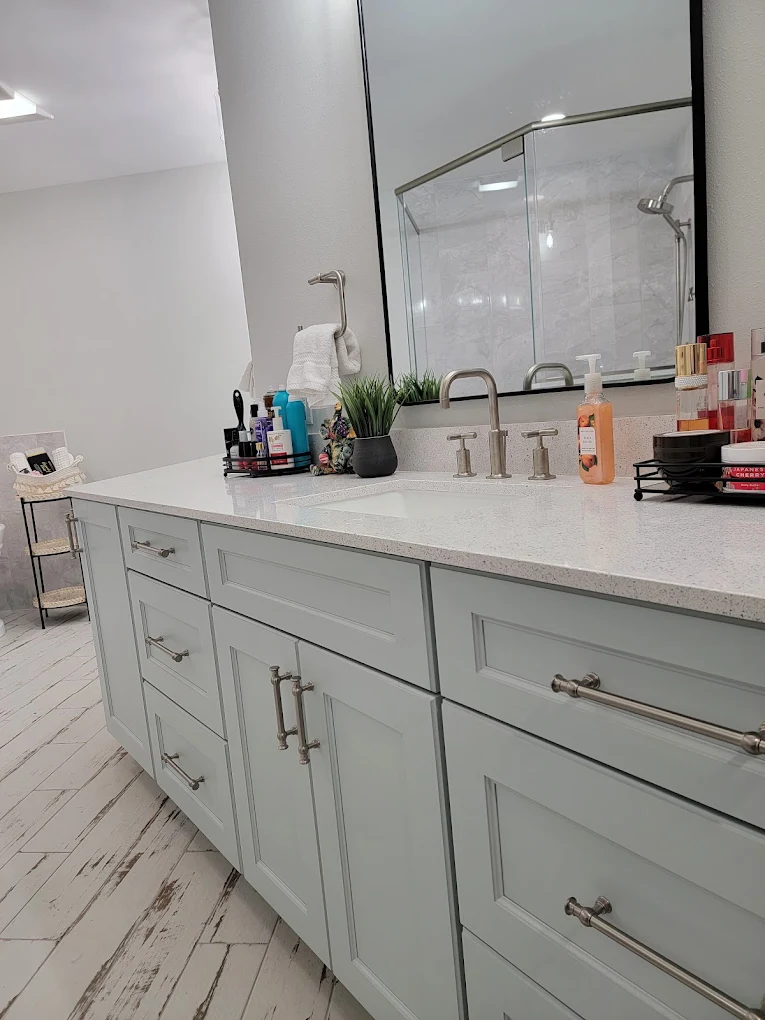 Bathroom vanity with light gray cabinets, a white countertop, and large mirrors