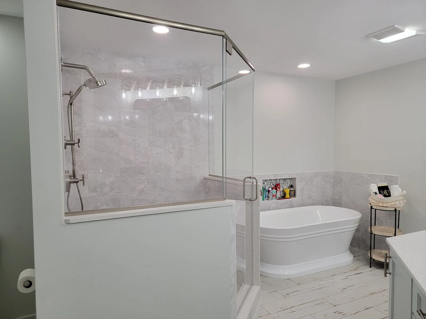 Bathroom with a glass-enclosed shower, freestanding bathtub, and marble-look tile