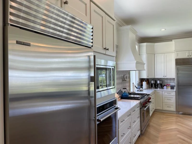 Kitchen with a stainless steel refrigerator, built-in ovens, and light-colored cabinets
