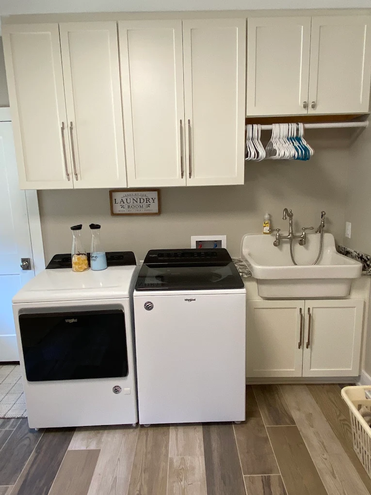 Laundry room with white cabinets, a washer and dryer, and a utility sink