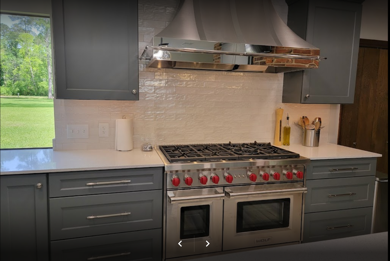 Kitchen with dark gray cabinets, a stainless steel range with red knobs, and a large range hood