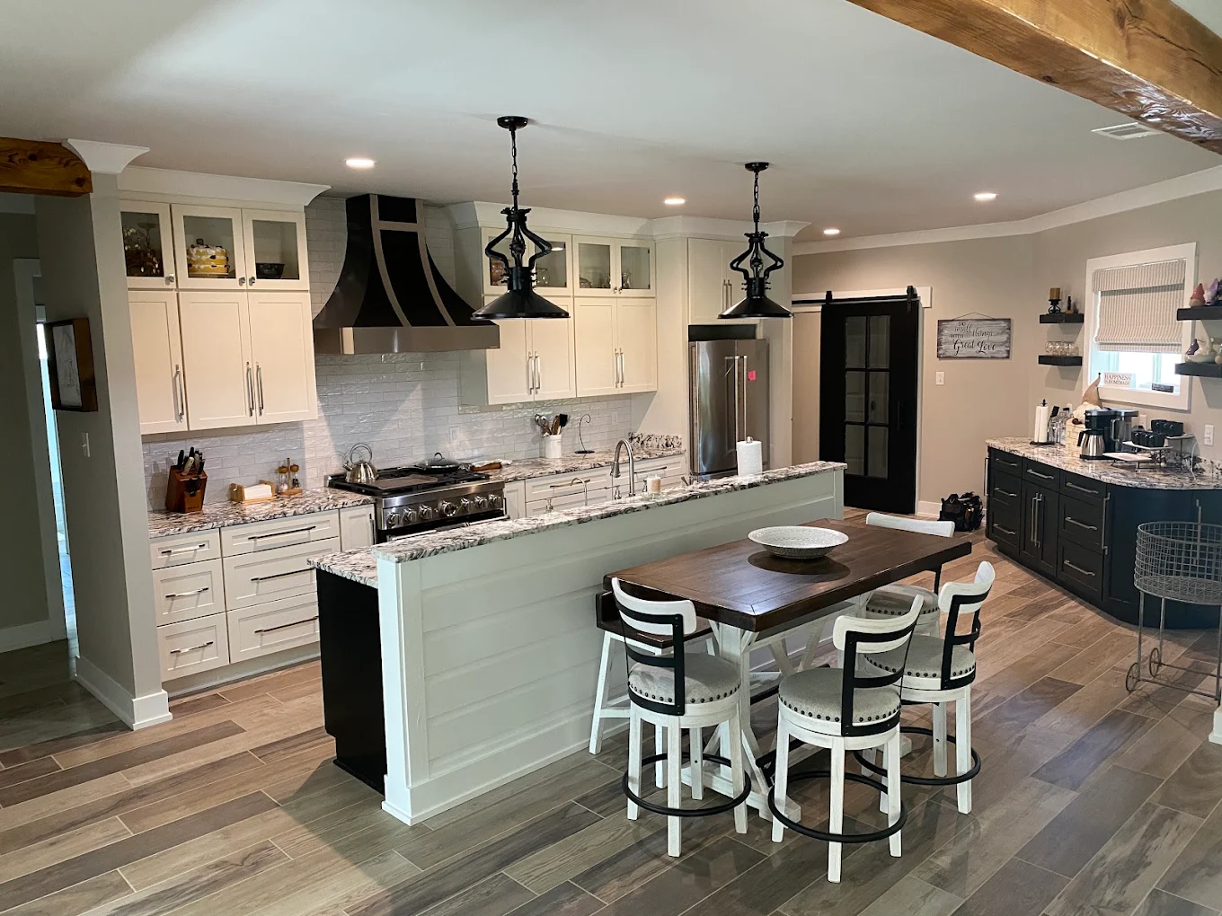 Kitchen with white cabinets, a pale green island, bar stools, and black pendant lights